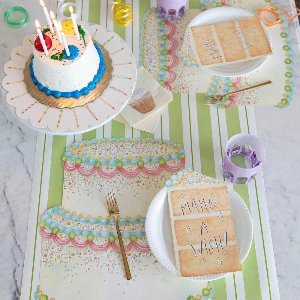 Children's birthday party setup with a small cake, plates, and napkins on a table.