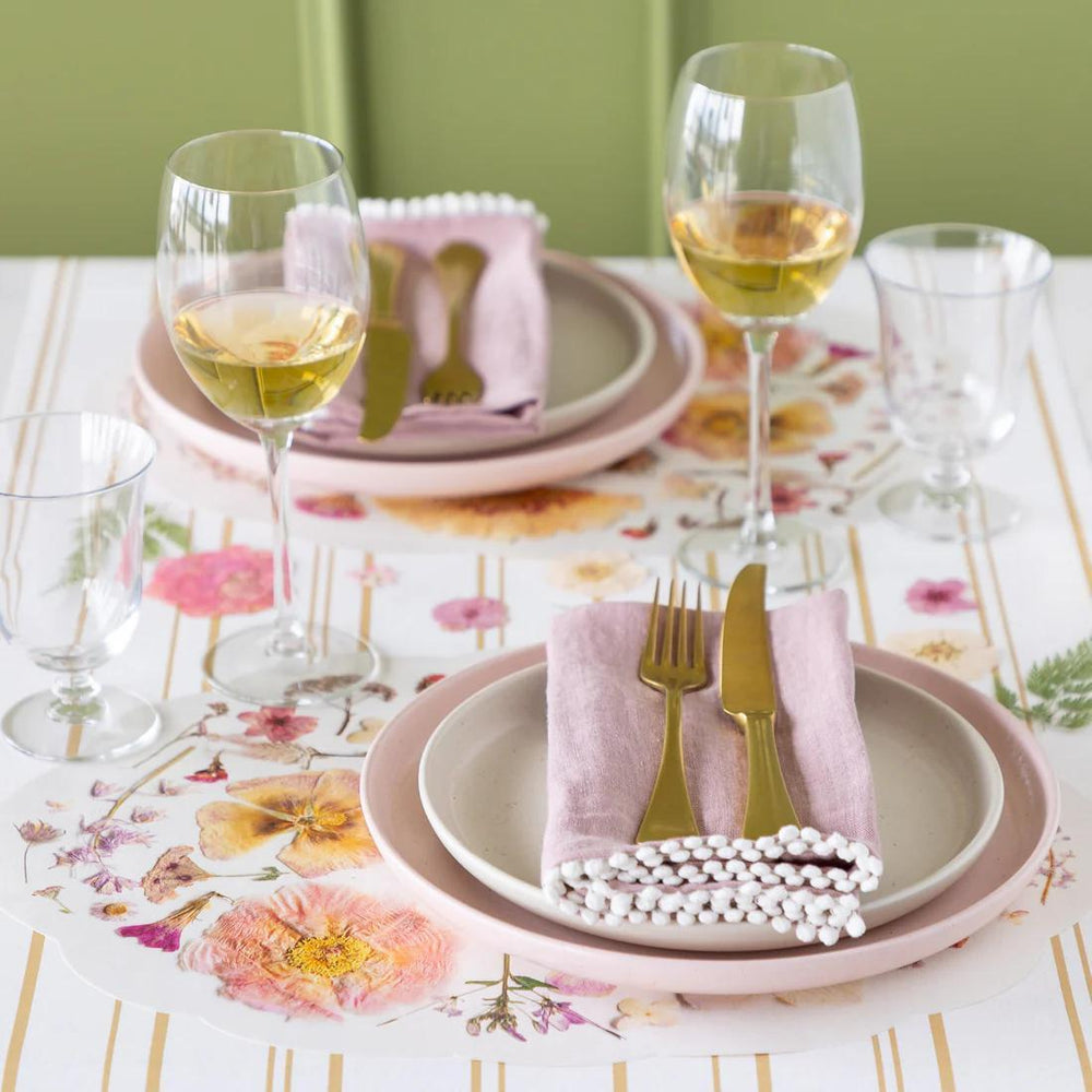 Dining table setting with floral tablecloth, plates, glasses, and cutlery.