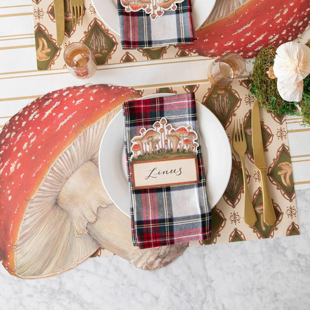 Decorative table setting with plaid napkins, mushrooms, and floral elements on a white surface.
