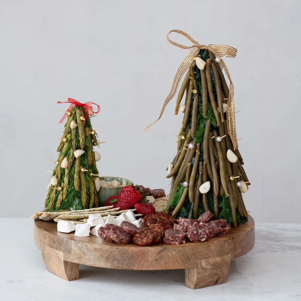 Decorative Christmas trees made of branches and twigs on a wooden board with food items.