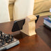 Wooden phone holder on a table with a chessboard and books in the background