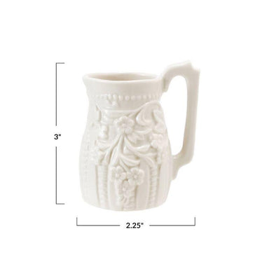 White ceramic pitcher with floral patterns and measurements on a white background
