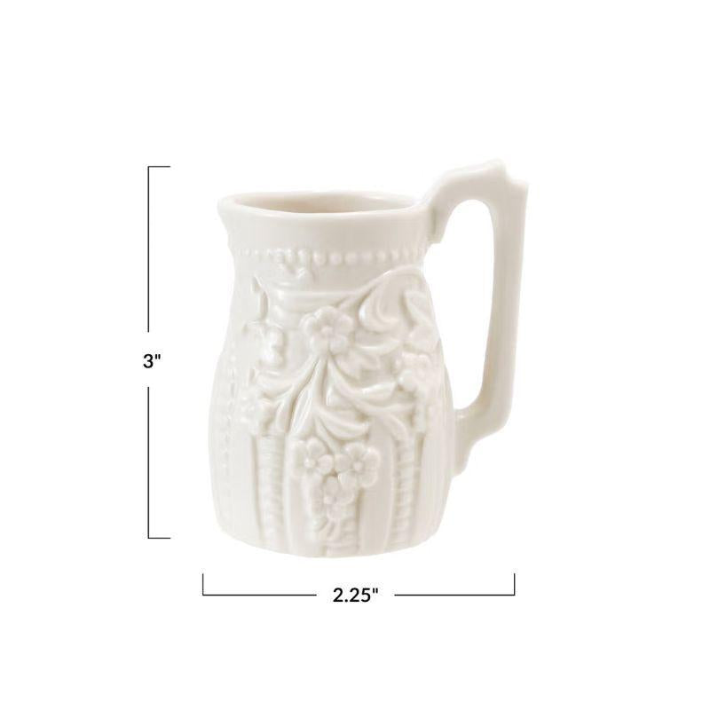 White ceramic pitcher with floral patterns and measurements on a white background