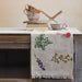 Table setting with floral tablecloth, cups, and books on a wooden surface.
