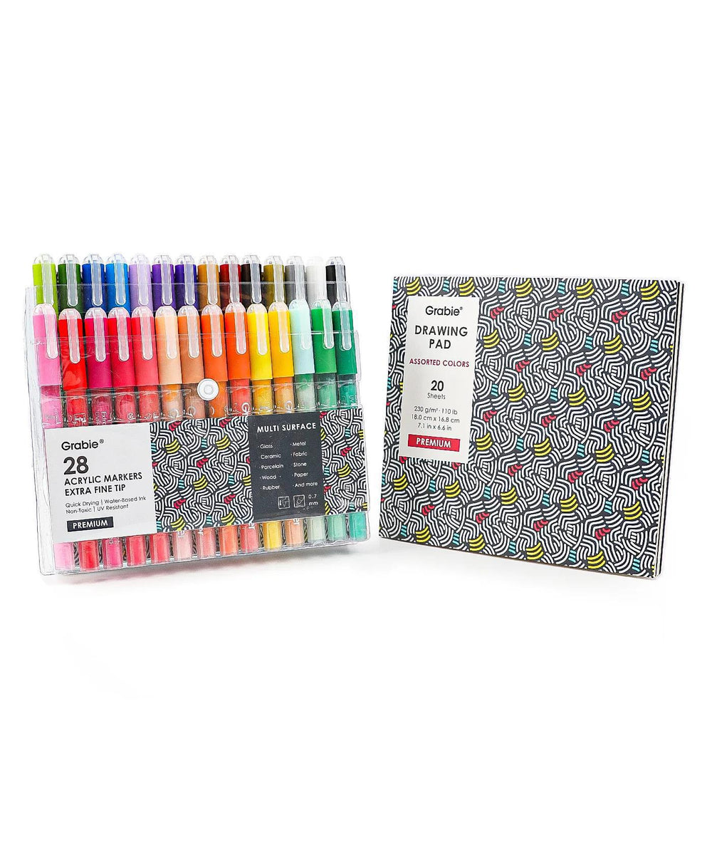Set of 28 acrylic markers and a drawing pad on a white background