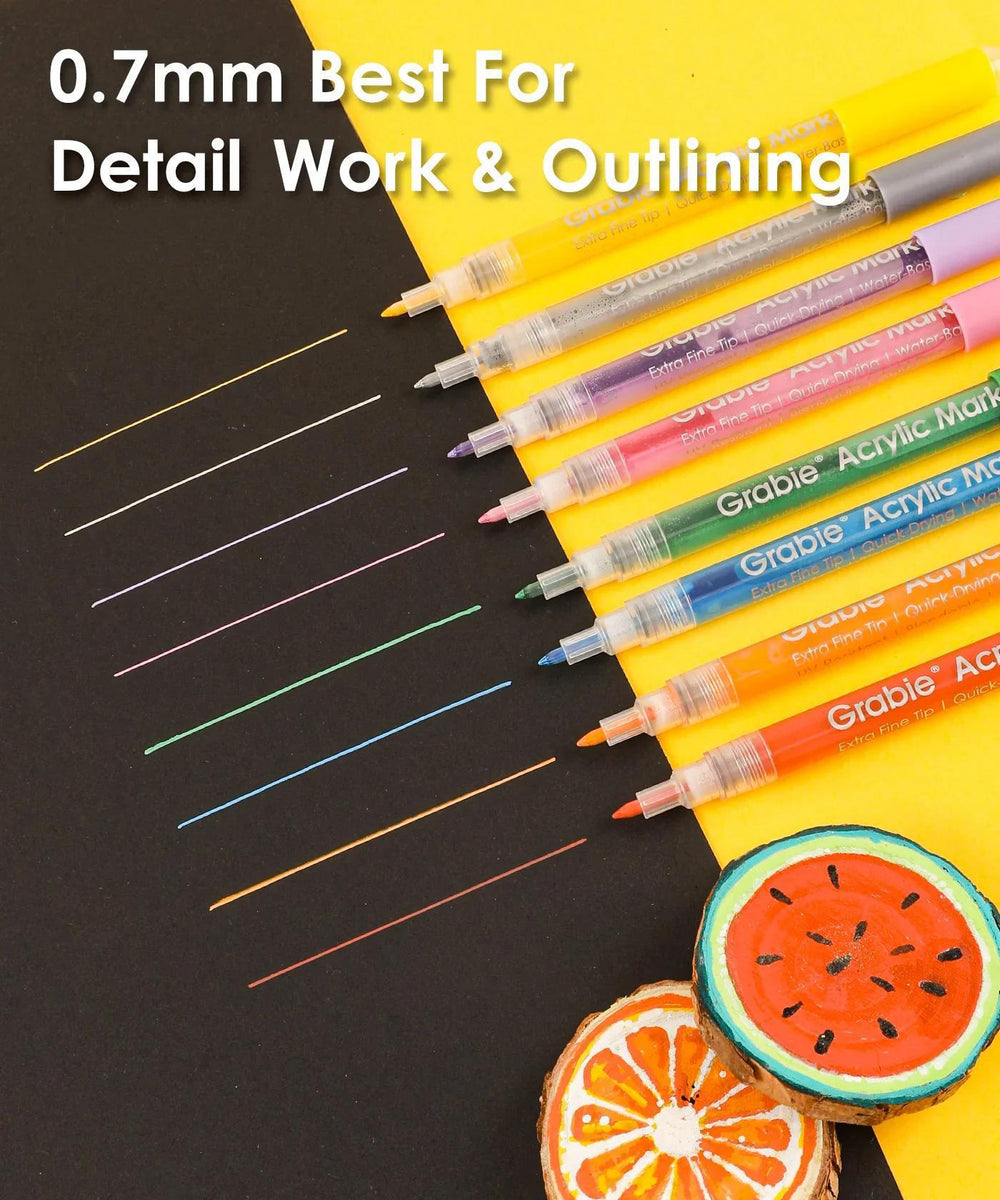 Set of colorful markers with lines drawn on paper and a watermelon-themed marker cap.