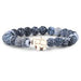 A beaded stretch bracelet featuring dark blue and white marbled round beads, with a central gold-toned elephant charm, shown on a plain white background.