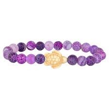 A beaded stretch bracelet featuring round purple marbled beads and a central gold-toned lotus flower charm, shown on a plain white background.