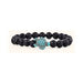 A beaded stretch bracelet featuring matte black round beads and a central turquoise-colored turtle charm with a textured pattern, set against a plain white background.