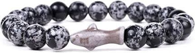 A beaded stretch bracelet featuring round black and white speckled stone beads with a central metallic silver fish charm, shown against a plain white background.