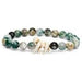 A beaded stretch bracelet made of polished green and white marbled stone beads, featuring a central white bone-like charm, shown on a plain white background.