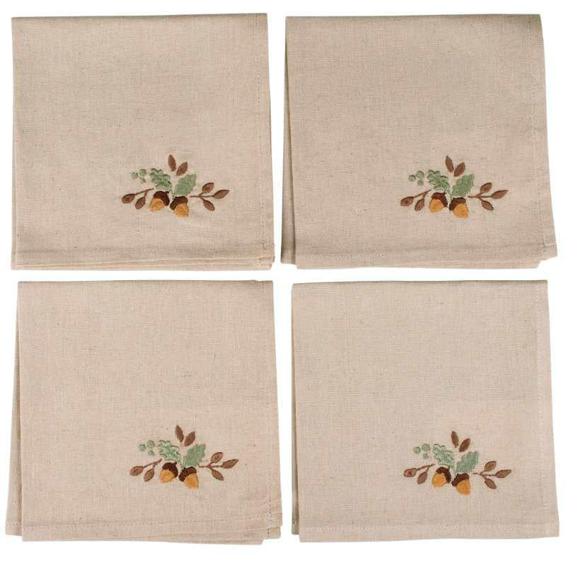 Four beige napkins with embroidered acorn and leaf designs on a white background