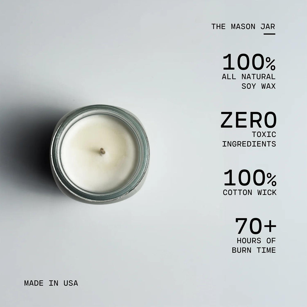 Candle in a mason jar with text highlighting its features on a light gray background