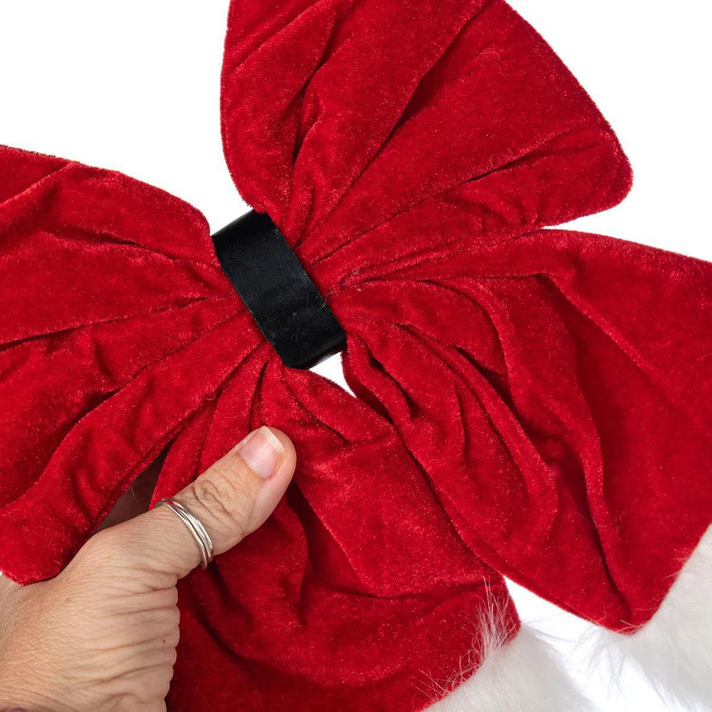 Red velvet bow with a hand adjusting it on a white background
