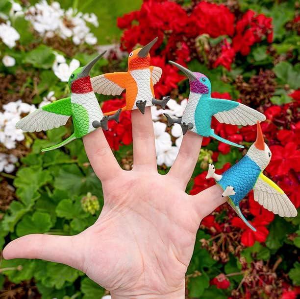 Colorful hummingbird finger puppets on a hand with flowers in the background