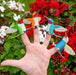 Colorful hummingbird finger puppets on a hand with flowers in the background