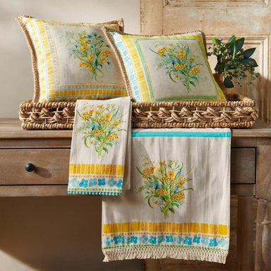 Decorative pillows and towels with floral patterns on a wooden surface.