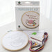 Embroidery kit with hoop, thread, and packaging on a white background