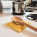 Wooden spoon on a yellow trivet on a stove