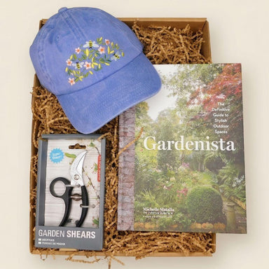 Garden-themed gift set with blue cap, 'Gardenista' book, and garden shears in a box.