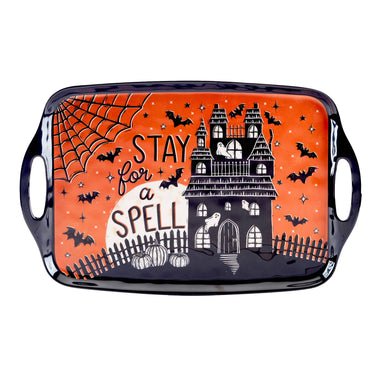 A rectangular black melamine serving tray with side handles, featuring a Halloween-themed orange and black printed design with a haunted house, bats, pumpkins, spiderwebs, stars, and the text 'STAY for a SPELL'.