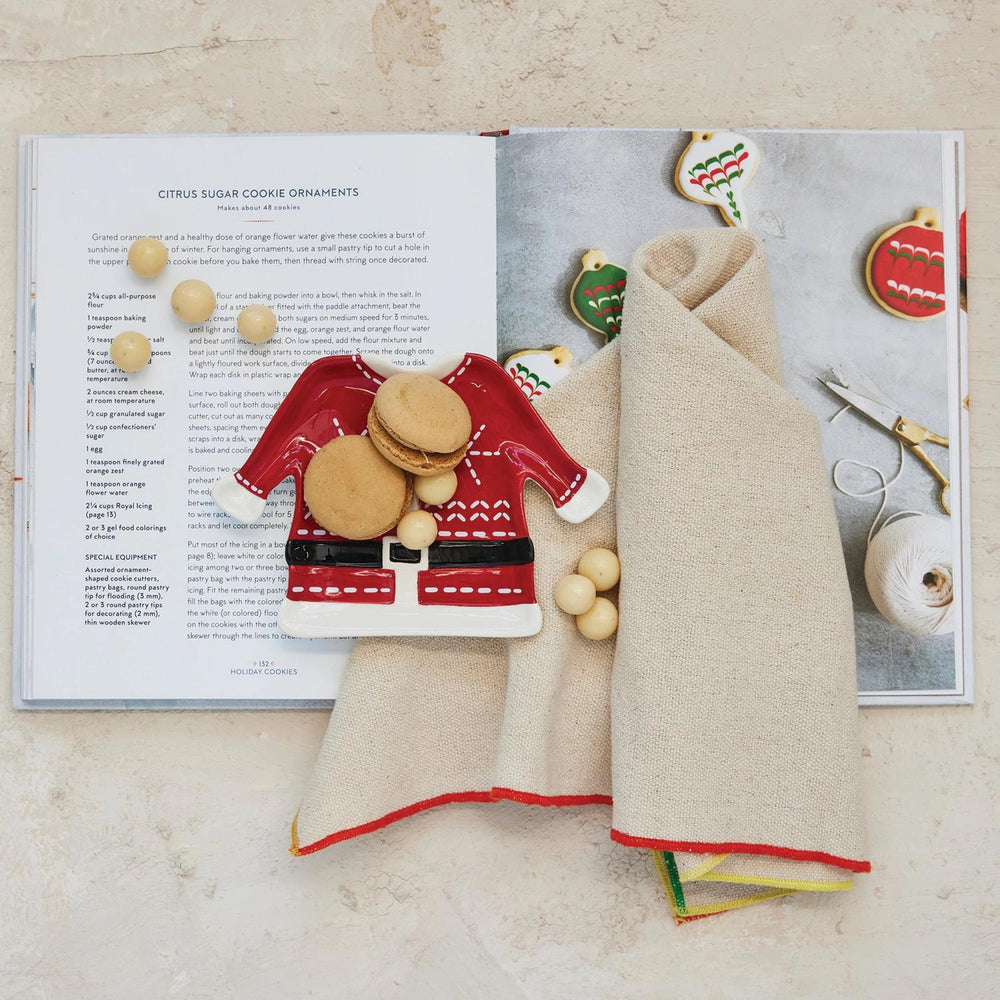 Decorative cookies shaped like a sweater and hat on an open book with recipe text.