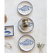 Set of ceramic plates with fish design on a textured white surface.