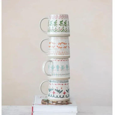 Stack of four patterned mugs on a white surface with a light background