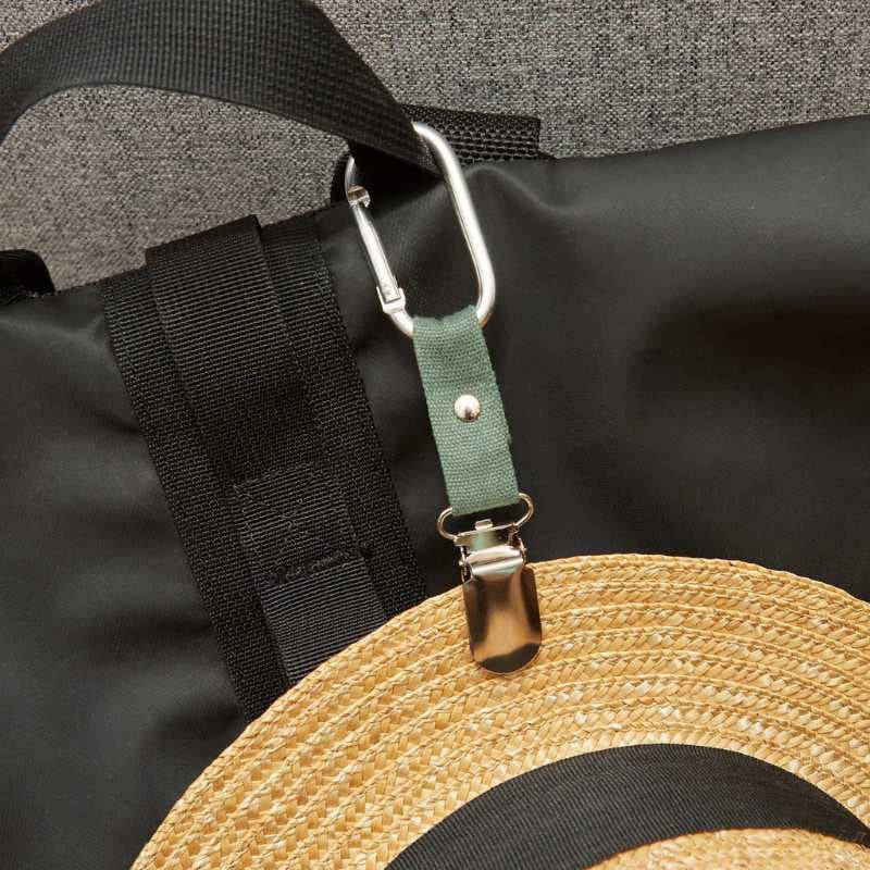 Hat clip, Strap with carabiner attached to a black bag, with a straw hat on top.