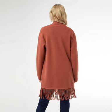 Person wearing a rust-colored cardigan with fringe details on a white background