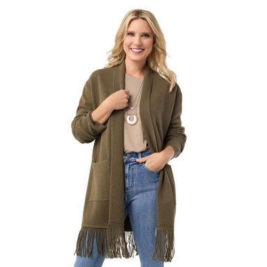 Woman wearing a green cardigan with fringe, beige top, and blue jeans on a white background