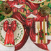 Christmas-themed table setting with red bows, gold cutlery, and holly leaves on a decorative paper background.