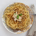 Plate of spaghetti with a garnish on a white tablecloth