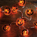String lights shaped like jack-o'-lanterns on a wooden surface