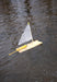 Model sailboat with a yellow body and white sail floating on water