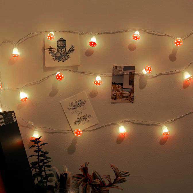 String lights on a wall with photos and cards attached
