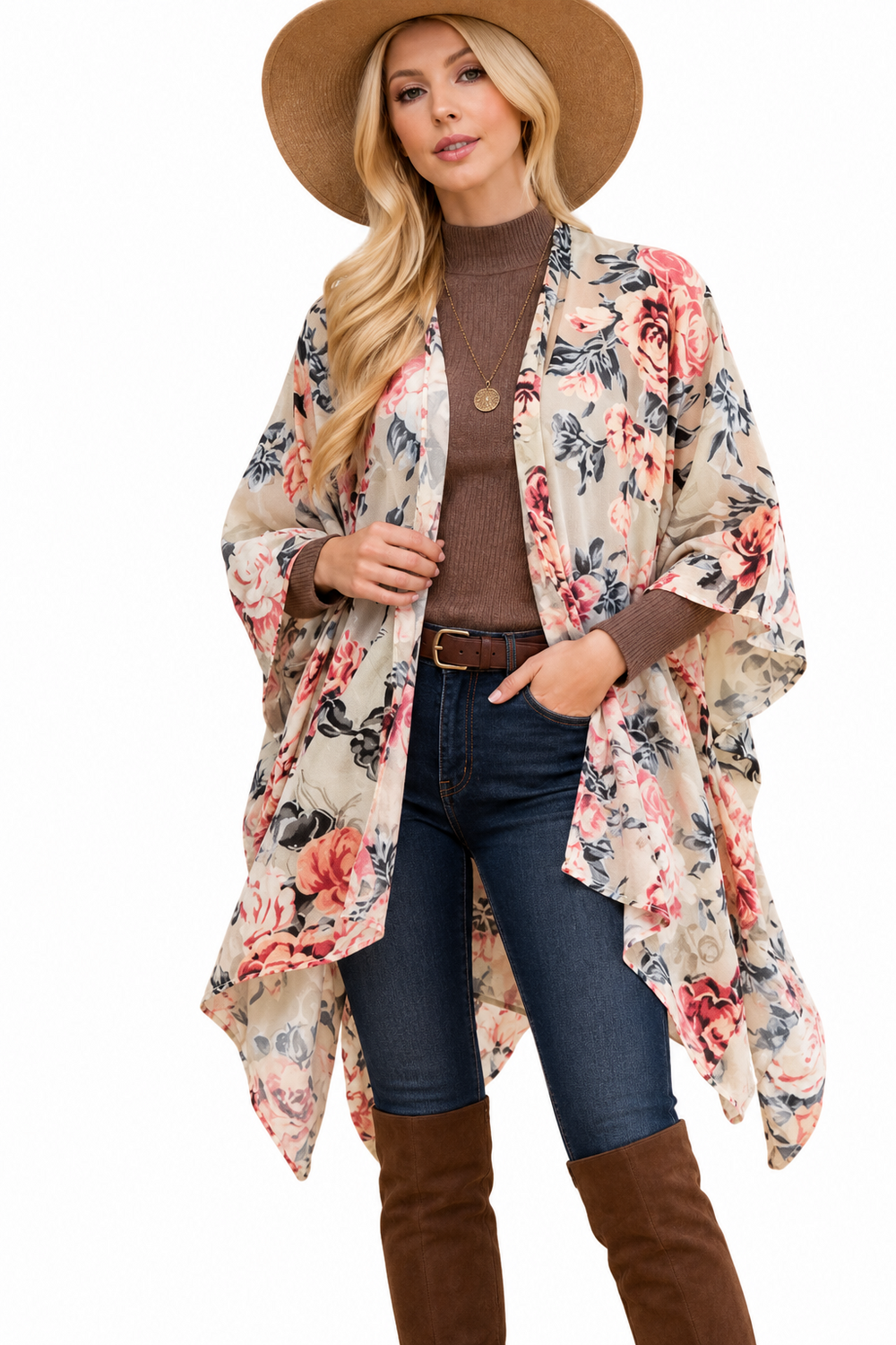 A woman modeling a long, open-front floral kimono cardigan with wide sleeves over a brown turtleneck, blue jeans, and brown knee-high boots, while wearing a wide-brimmed brown hat against a plain white background.