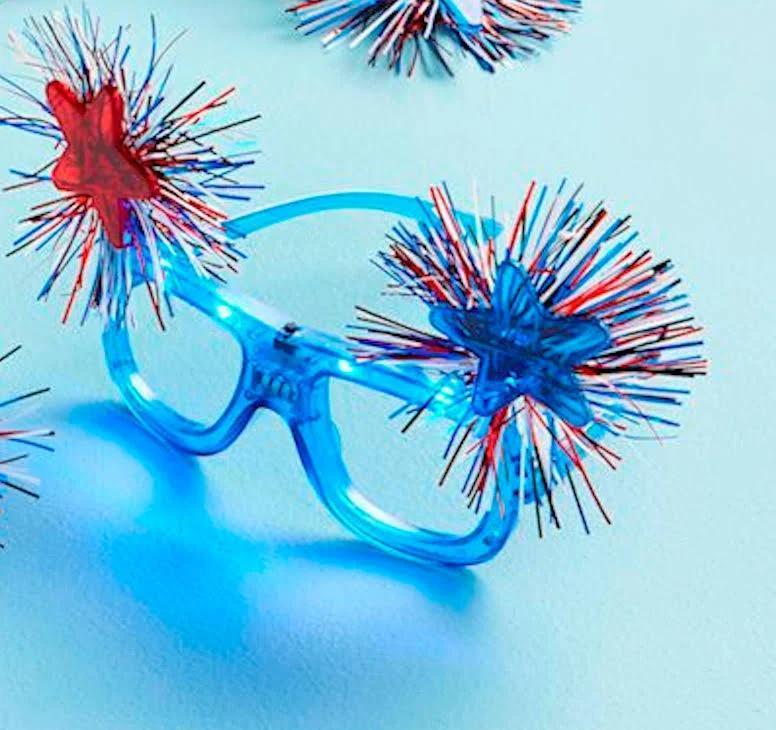 Glasses with red and blue decorative pom-poms on a light blue background
