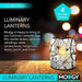 Luminary lantern on a wooden surface with blurred lights in the background, featuring Modgy branding.