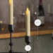 Two lit candles in black holders with measurements on a blurred background
