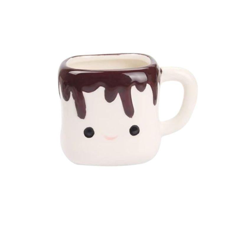 Ceramic mug shaped like a cartoon character with chocolate sauce on top against a white background