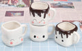 Set of three ceramic mugs with face designs on a checkered surface.