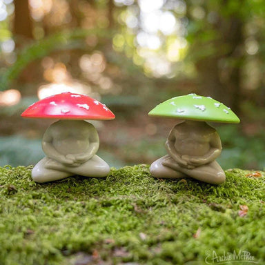 Two small figurines with mushroom hats on a mossy surface with a blurred natural background