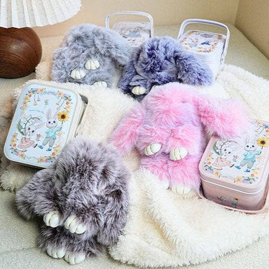 Two fluffy bunny slippers in gray and pink with matching lunch boxes on a soft surface.