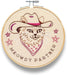 Embroidery hoop with a cat wearing a cowboy hat and bandana, and the text 'Meowy Partner'.