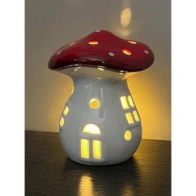Mushroom-shaped night light with red cap and white body on a dark surface.