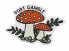 A die-cut sticker featuring two red and white spotted mushrooms with green leaves and the text 'PORT GAMBLE' arched above them, shown on a plain white background.