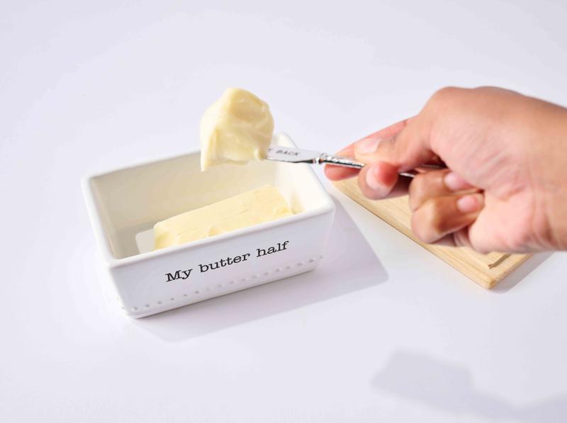 Person taking a scoop of butter from a container labeled 'My butter half' on a white background