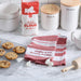 Baking-themed kitchen scene with flour bag, cookies, towel, and rolling pin on a marble countertop.