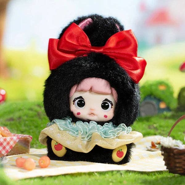 Toy figure with a red bow on a picnic blanket with a blurred outdoor background